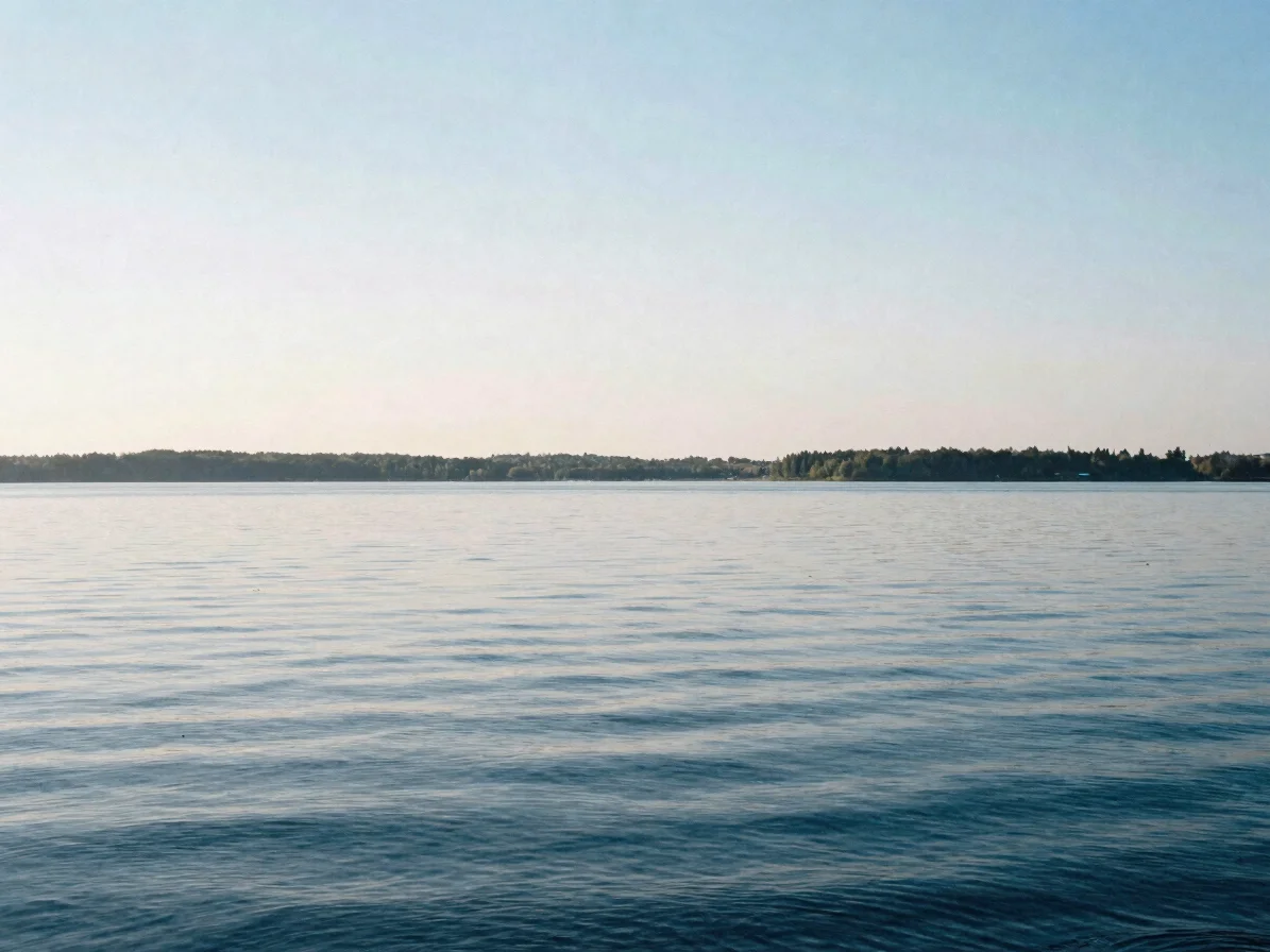 Natural editorial photograph of a calm lakeside morning, soft day